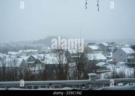 Un tranquillo quartiere periferico è coperto da uno spesso strato di neve, con case oscurate da una morbida foschia invernale. Foto Stock