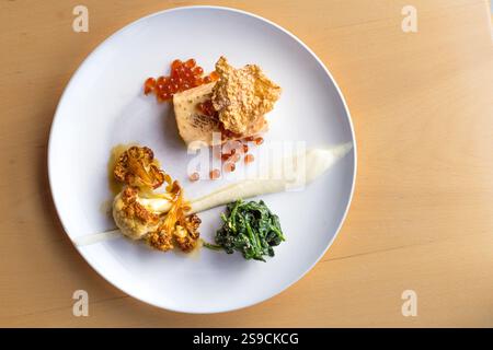 Piatto gourmet con salmone, spinaci, cavolfiore e Roe su elegante piatto bianco Foto Stock