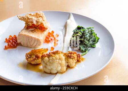 Piatto gourmet con salmone, spinaci, cavolfiore e Roe su elegante piatto bianco Foto Stock