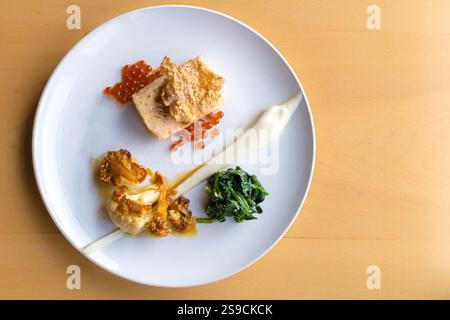 Piatto gourmet con salmone, spinaci, cavolfiore e Roe su elegante piatto bianco Foto Stock
