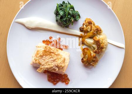 Piatto gourmet con salmone, spinaci, cavolfiore e Roe su elegante piatto bianco Foto Stock