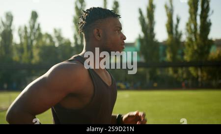 Vista laterale corridore jogger etnico giovane uomo che corre all'aperto stile di vita attivo corsa mattutina motivato ragazzo afroamericano atleta fitness maschile corsa Foto Stock