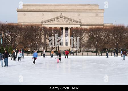 Foto della pista di pattinaggio su ghiaccio con pattinatori presso il giardino di sculture della National Gallery of Art con il National Archives Museum sullo sfondo. Foto Stock