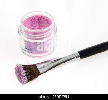 Pigmento glitterato viola e pennello per il trucco con manico nero impreziosito da uno sfondo bianco e pulito, che ritrae elementi di bellezza, creatività e bellezza Foto Stock