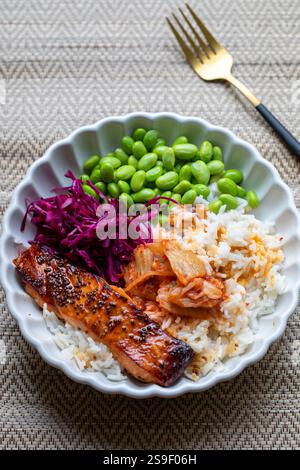 Cena sana con riso, salmone, semi di soia, cavolo rosso e kimchi Foto Stock