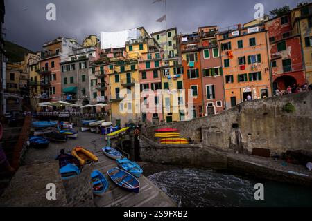 Piccole e colorate barche nel villaggio di Manarola, in Italia. Case colorate e a più piani si trovano adiacenti l'una all'altra vicino alla vivace costa. Foto Stock