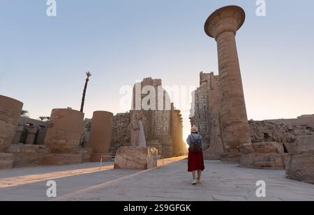 Il viaggiatore felice di donna esplora le rovine dell'antico tempio di Karnak nella città patrimonio di Luxor in Egitto. Gigantesca fila di colonne con gerogliera scolpita Foto Stock
