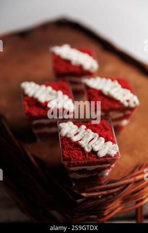 una fetta di torta di velluto rosso in tazza condita con una bella crema sul tavolo di legno, vista dall'alto, primo piano. Foto Stock