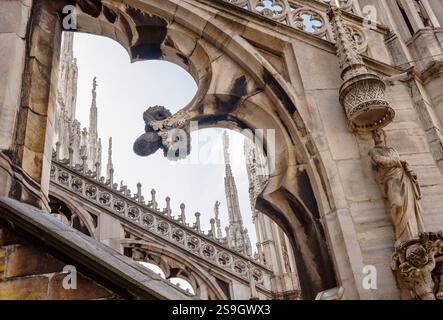 Dettagli intricati del Duomo di Milano con archi gotici, statue, guglie e sculture ornate. La straordinaria maestria artigianale mette in risalto la ricca storia e l'arte Foto Stock