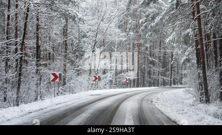 Vista in prima persona sulla strada innevata, svolta brusca. Fare attenzione a guidare un'auto in inverno Foto Stock
