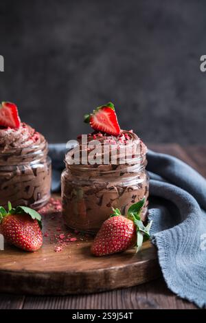Deliziosa mousse al cioccolato ricoperta di fragole fresche e liofilizzate in vasetti di vetro Foto Stock
