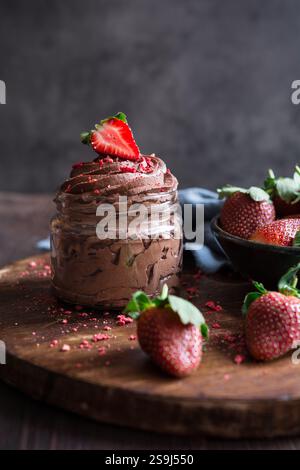 Deliziosa mousse al cioccolato ricoperta di fragole fresche e liofilizzate in vasetti di vetro Foto Stock
