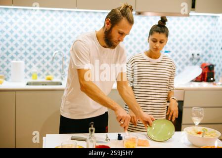 Una coppia felice che si diverte a cucinare insieme in una cucina moderna ed elegante Foto Stock