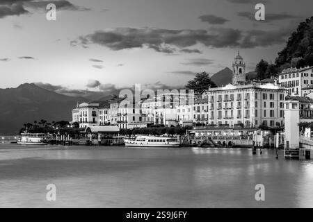 Il lago di Como riflette il villaggio di Bellagio al tramonto con un cielo spettacolare e montagne alpine sullo sfondo, fotografie in bianco e nero dalla Lombardia, Italia Foto Stock
