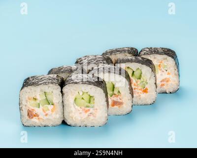 Fotografia in studio del rotolo di Maki con cetriolo e mousse di salmone avvolta in nori. Isolato su sfondo blu chiaro fisso Foto Stock