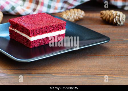 Pezzo di torta di velluto rosso in piastra su tavolo rustico, a fette quadrate, copia spazio fuoco selettivo Foto Stock