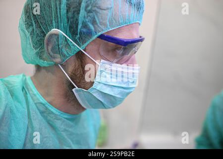 Vista laterale di un chirurgo con attrezzatura di protezione completa, con un aspetto mirato Foto Stock
