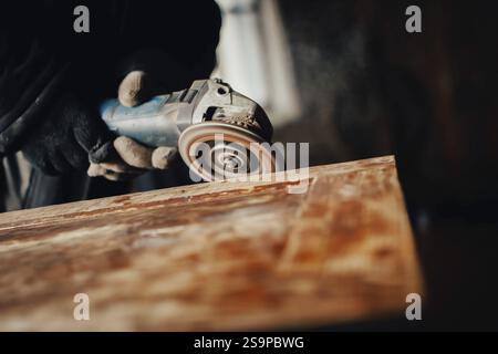 Primo piano di un falegname utilizzando una smerigliatrice sul legno, creando polvere e rivelando la consistenza Foto Stock