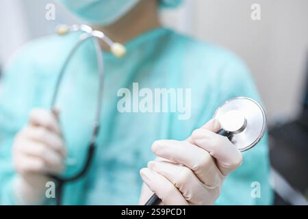 Primo piano di mani con i guanti che tengono la parte metallica dello stetoscopio Foto Stock