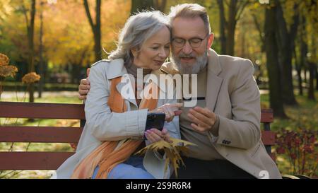 Coniugato caucasico coppia felice famiglia di mezza età donna matura uomo remoto pagamento ordine online con cellulare carta di credito pensionato marito moglie uso Foto Stock