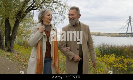 Coppia sposata di mezza età moglie dai capelli grigi marito in elegante capospalla che cammina insieme passeggiata romantica nel parco autunnale famiglia caucasica donna matura uomo Foto Stock