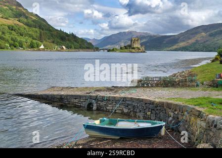 Guardando verso sud lungo Loch Duich fino al castello di Eilean Donan, accanto alla strada principale A87 per Skye, a nord di Morvich. Barca e attrezzatura da pesca sullo scalo. Rinomato, Foto Stock