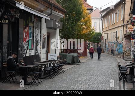 Persone anziane che si godono una passeggiata lungo la strada acciottolata di lubiana, slovenia, passando accanto a un caffè all'aperto Foto Stock
