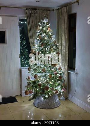 Albero di Natale decorato in stile moderno con luci bianche fredde e decorazioni in oro opaco Foto Stock
