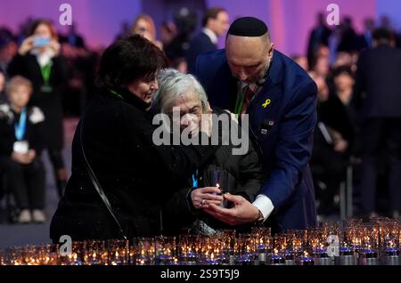 Una sopravvissuta di Auschwitz viene confortata mentre posa una candela durante le commemorazioni ad Auschwitz-Birkenau in Polonia per celebrare i 80 anni dalla liberazione del campo di concentramento il 27 gennaio 1945. Data foto: Lunedì 27 gennaio 2025. Foto Stock