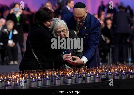Una sopravvissuta di Auschwitz viene confortata mentre posa una candela durante le commemorazioni ad Auschwitz-Birkenau in Polonia per celebrare i 80 anni dalla liberazione del campo di concentramento il 27 gennaio 1945. Data foto: Lunedì 27 gennaio 2025. Foto Stock