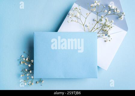 Mockup con biglietto d'auguri o invito, bianco turchese vuoto con decorazioni floreali su sfondo bue, spazio per copie. Elegante mockup creativo con gesso bianco Foto Stock