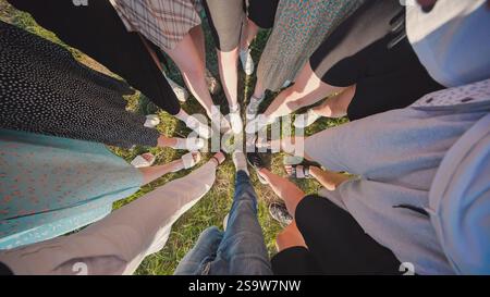 Gruppo di studenti delle scuole superiori in piedi insieme in cerchio all'aperto, gambe e scarpe che formano uno schema sull'erba Foto Stock