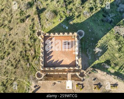 Vista aerea del castello di Nogales in Spagna con torre omaggio, merlature e 4 torri circolari sulla cima di una collina Foto Stock