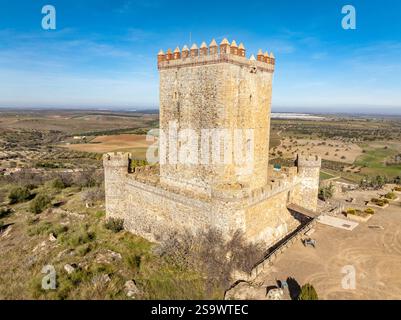 Vista aerea del castello di Nogales in Spagna con torre omaggio, merlature e 4 torri circolari sulla cima di una collina Foto Stock