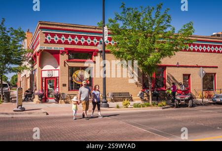 Winslow, Arizona USA - 4 giugno 2018: Famiglia che attraversa la strada di fronte al SIPP Shoppe, una caffetteria retrò in uno storico edificio bancario di Standing On the Foto Stock
