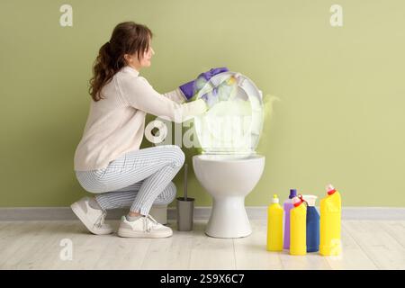 Giovane donna che pulisce la ciotola sporca del bagno in bagno Foto Stock