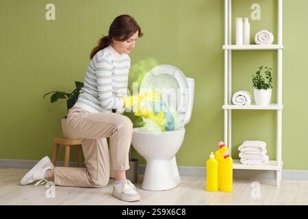 Giovane donna che pulisce la ciotola sporca del bagno in bagno Foto Stock