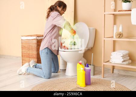 Giovane donna che pulisce la ciotola sporca del bagno in bagno Foto Stock