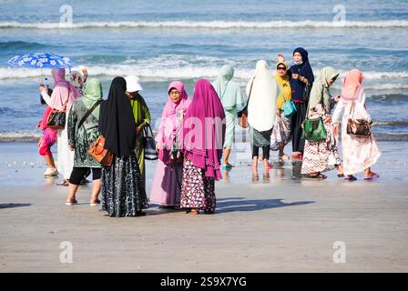 Donne in abbigliamento tradizionale che si godono la spiaggia e scattano foto a Kuta Beach, Bali Foto Stock