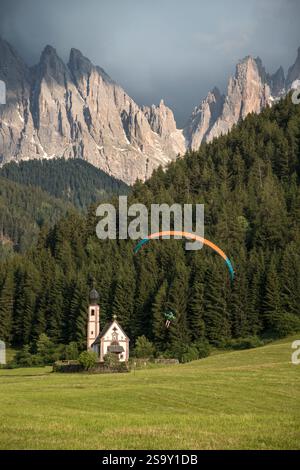 Italia, Dolomiti. Deltaplano di fronte alla chiesa e alla foresta. Foto Stock