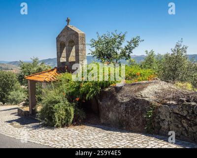 Piccolo edificio in pietra con panchina in pietra all'ingresso dell'antico borgo medievale di Monsanto. Foto Stock