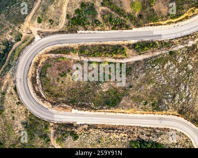 Una tortuosa strada asfaltata che attraversa zone con pochi alberi in autunno. Un'autostrada curva a S. Foto Stock