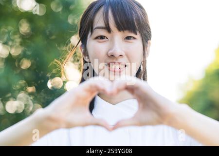 Donna in bianco che forma un cuore con entrambe le mani Foto Stock
