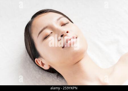 Giovane donna sdraiata in un salone di bellezza illuminato Foto Stock