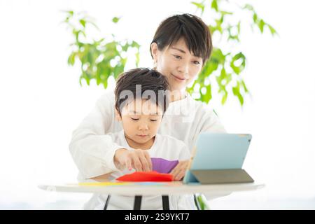 Genitori e bambini che fanno l'origami mentre guardano un tablet PC Foto Stock