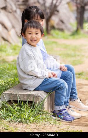 Sorridente bambino seduto su una panchina sorriso Foto Stock