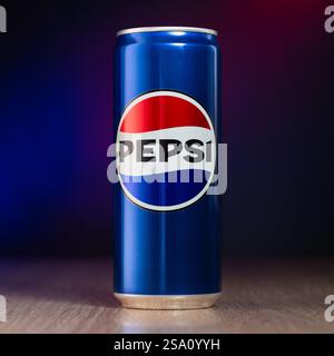 Stira una lattina di cola sul tavolo con foto blu e rosso sfocati. Pubblicità di coca Foto Stock