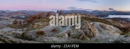 Panorama del Lake District all'alba visto dalla falesia nera con stile di legno sopra un muro di pietra. Vedute aeree verso Windermere e Langdale. Foto Stock