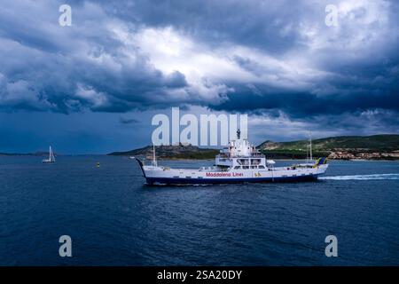 Il traghetto Pace di Maddalena Lines, che corre tra il porto di Palau e l'isola di la Maddalena, nuvole di tempesta buie in lontananza. Foto Stock