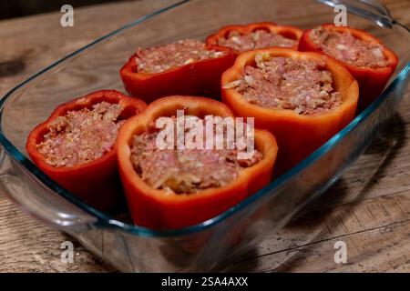 Gefüllte Paprika mit Hackfleischmischung in einer Auflaufform 28.01.25, Selters: Symbolfoto, Illustrationsbild, Symbolbild, Illustrationsfoto, Alltagsszene Gefüllte Paprika mit Hackfleischmischung in einer Auflaufform Frische, rote Paprikaschoten, gefüllt mit einer würzigen Hackfleischmischung, stehen in einer Glasauflaufform auf einem rustikalen Holztisch. Die Zubereitung ist noch nicht abgeschlossen, da die Paprika roh und ungebacken sind. Dieses klassische Gericht ist ein beliebtes Rezept in vielen Küchen weltweit. . Selters Hessen Germania *** peperoni ripieni con impasto di carne macinata in una c Foto Stock
